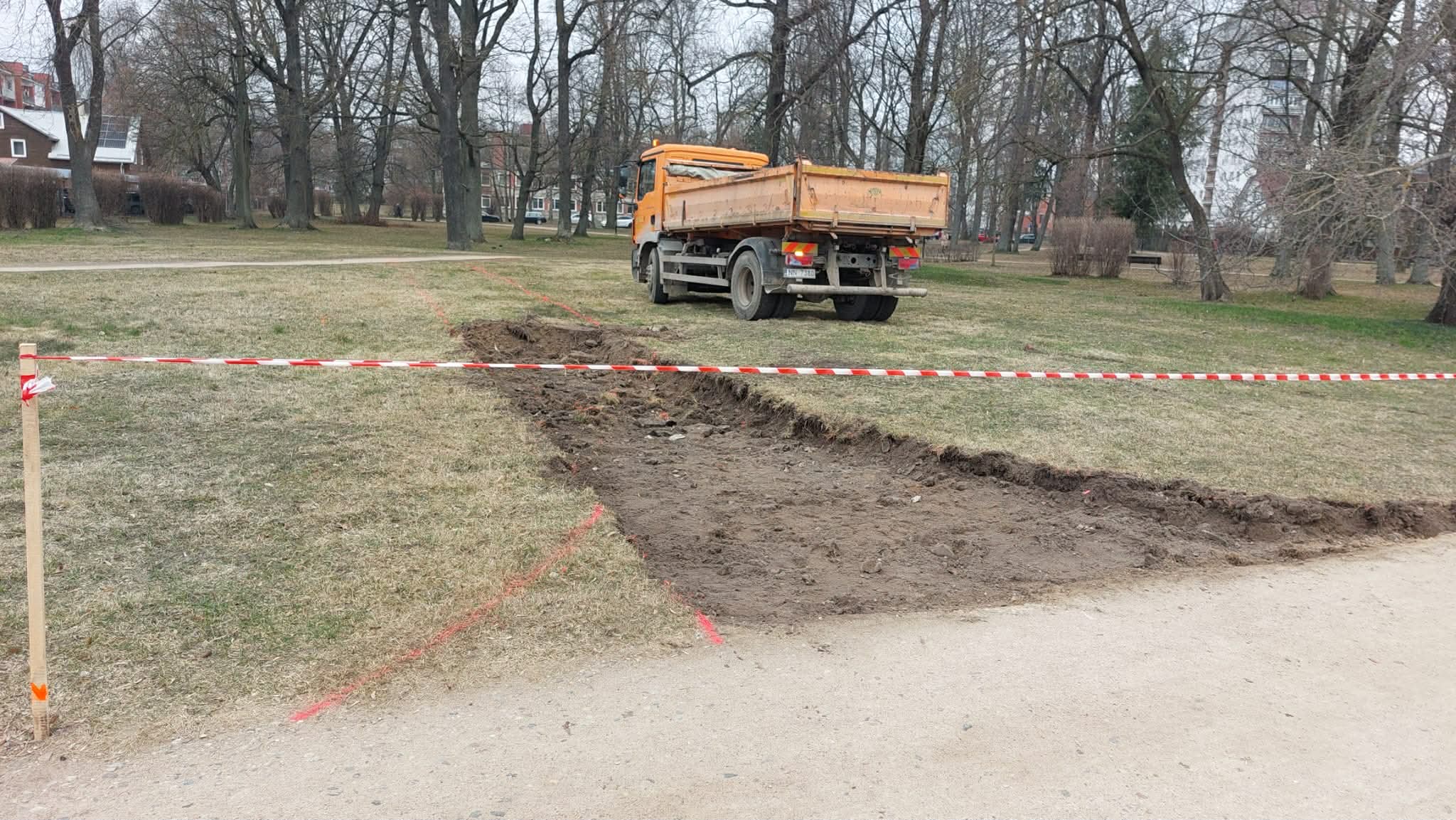Alunāna parka teritorijā notiek būvdarbi. Izrakta tranšeja gar celiņu un blakus stāv kravas automašīna. Teritorija ir norobežota ar brīdinājuma lentu.