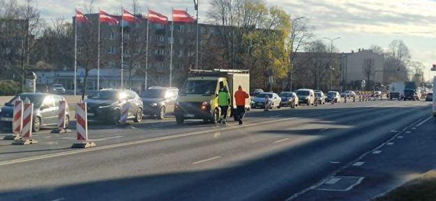 liela-iela_small Ceļa remontdarbi Lielajā ielā pie Hercoga Jēkaba laukuma – satiksme vienā joslā, automašīnu rinda un divi ceļstrādnieki pie darba furgona.
