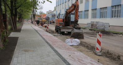 Brieza_iela Ielas pārbūve pie ēkas. Ekskavators un strādnieki veic darbus, uzstāda norobežojumus. Ietve no dažādu krāsu bruģa.