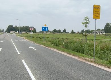 Prohorova zīme Prohorova iela pie dzelzceļa pārbrauktuves. Redzama asfaltēta brauktuve ar ceļa zīmēm, dzelzceļa sliedes, zālājs un informatīvā zīme par satiksmes organizācijas izmaiņām.