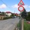 Saules iela ar grants segumu un māju rindām; priekšplānā ceļa zīmes „Ceļa darbi” un „Braukt aizliegts”.