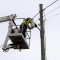 Elektriķis pacēlāja grozā uzstāda jaunu ielas apgaismojuma lampu pie koka staba.